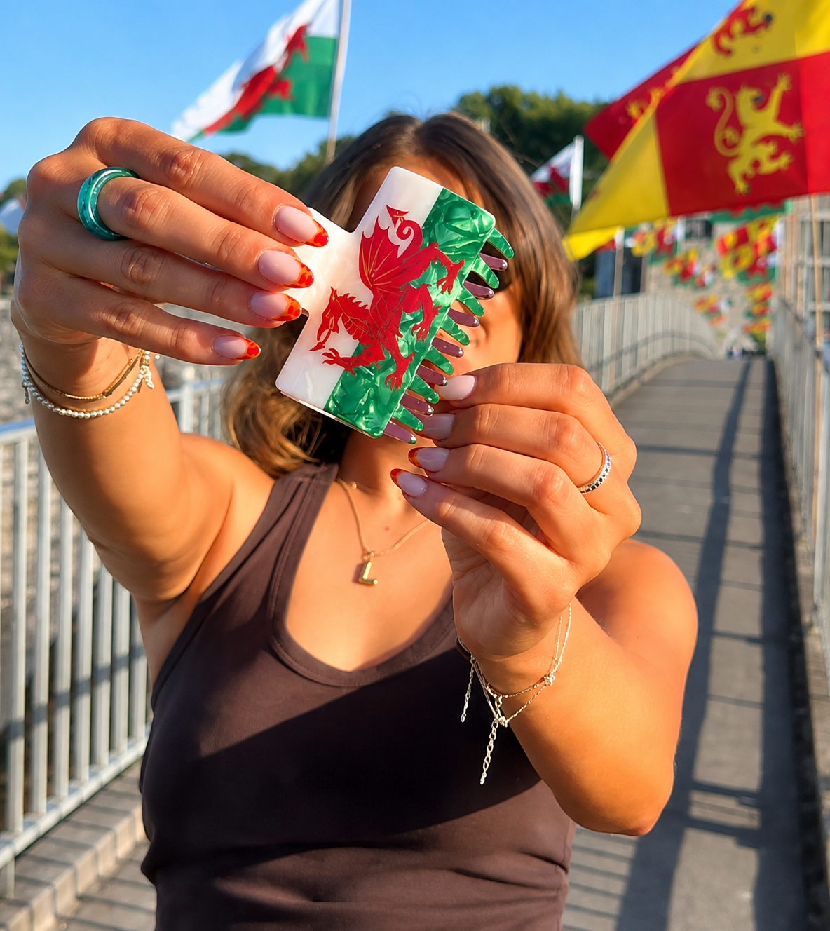 Woman holding a Welsh flag claw clip in front of Welsh flags